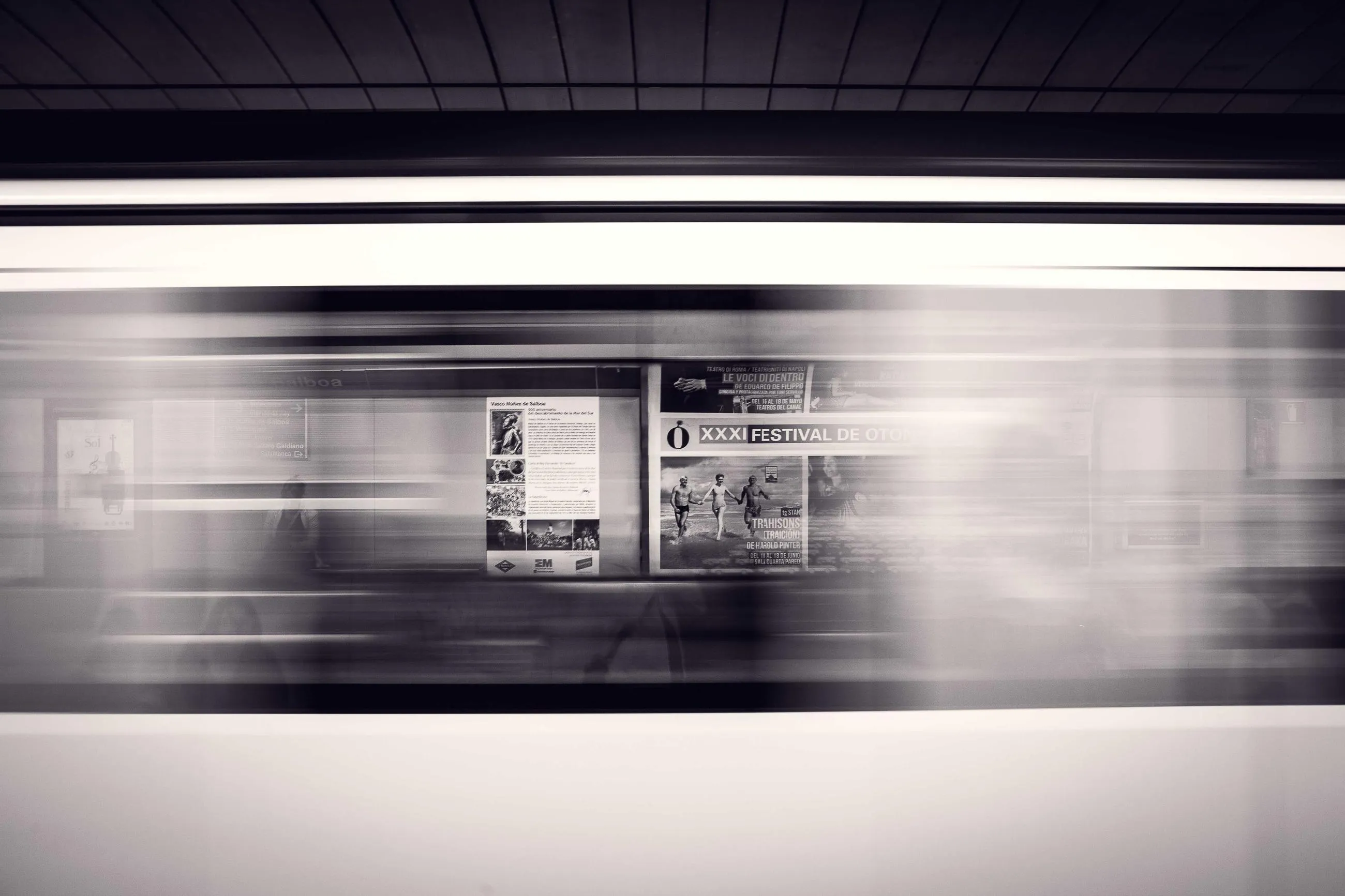 A train blurring through a station platform into horizontal bands of light.