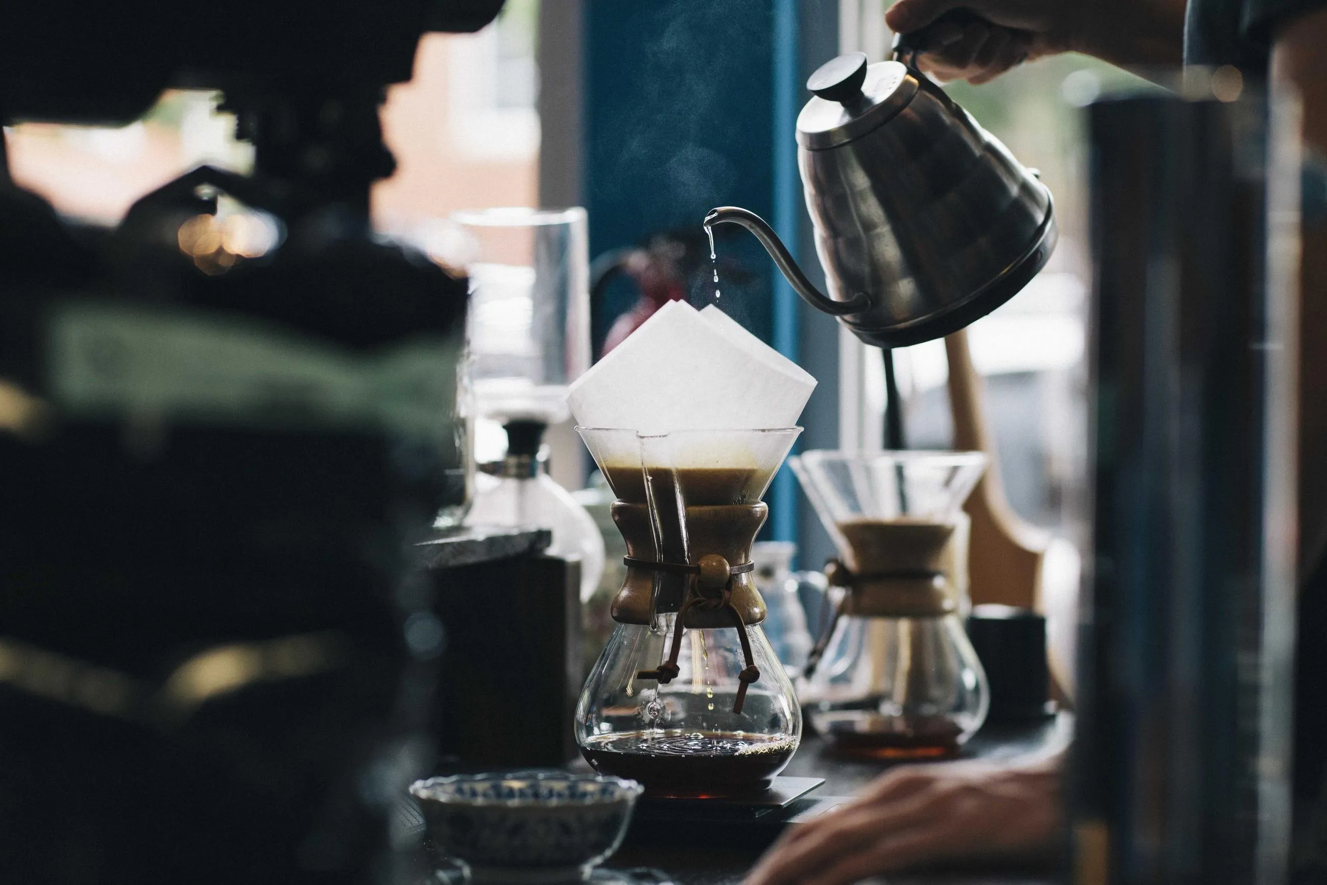 Coffee being poured over a paper filter on a dark cafe counter.
