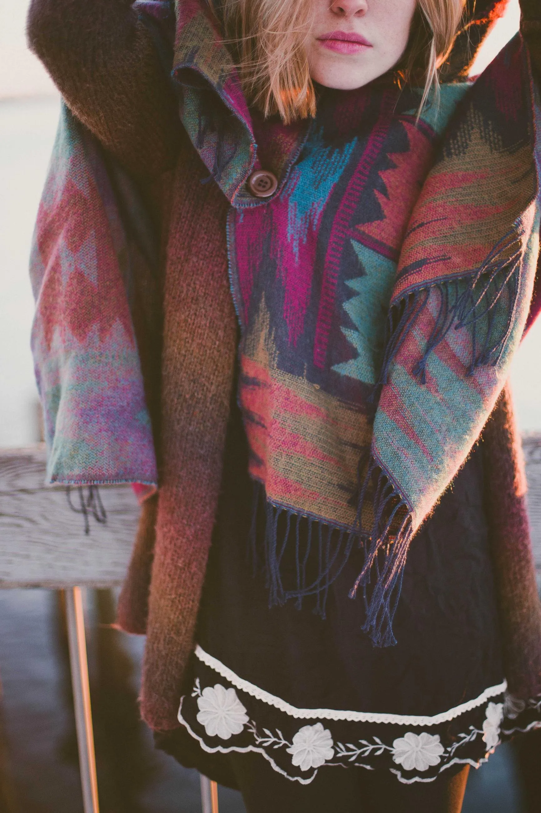 A model wrapped in a patterned wool blanket, her face cropped at the lips.