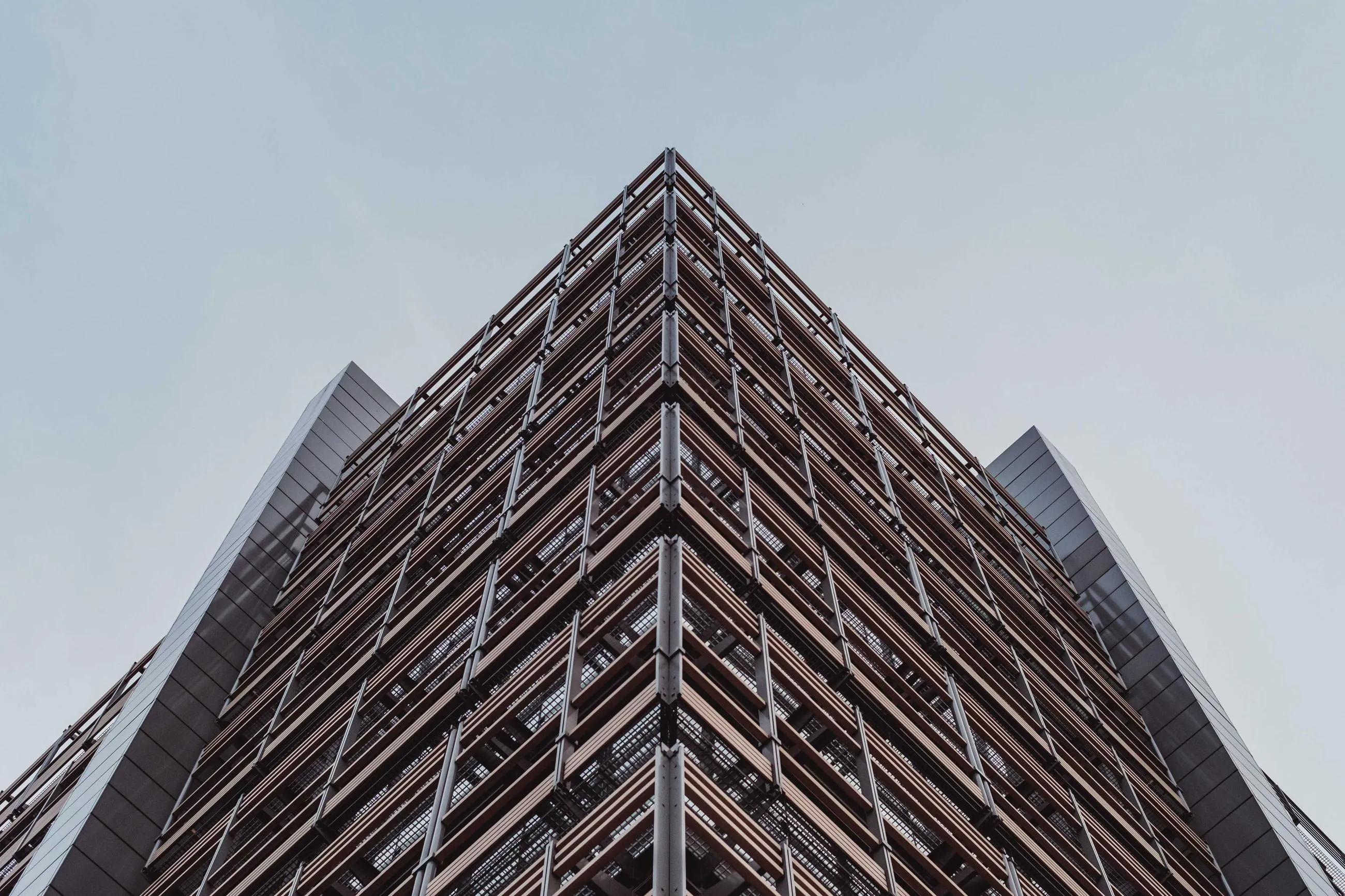 The sharp corner of a timber-clad building seen from below.