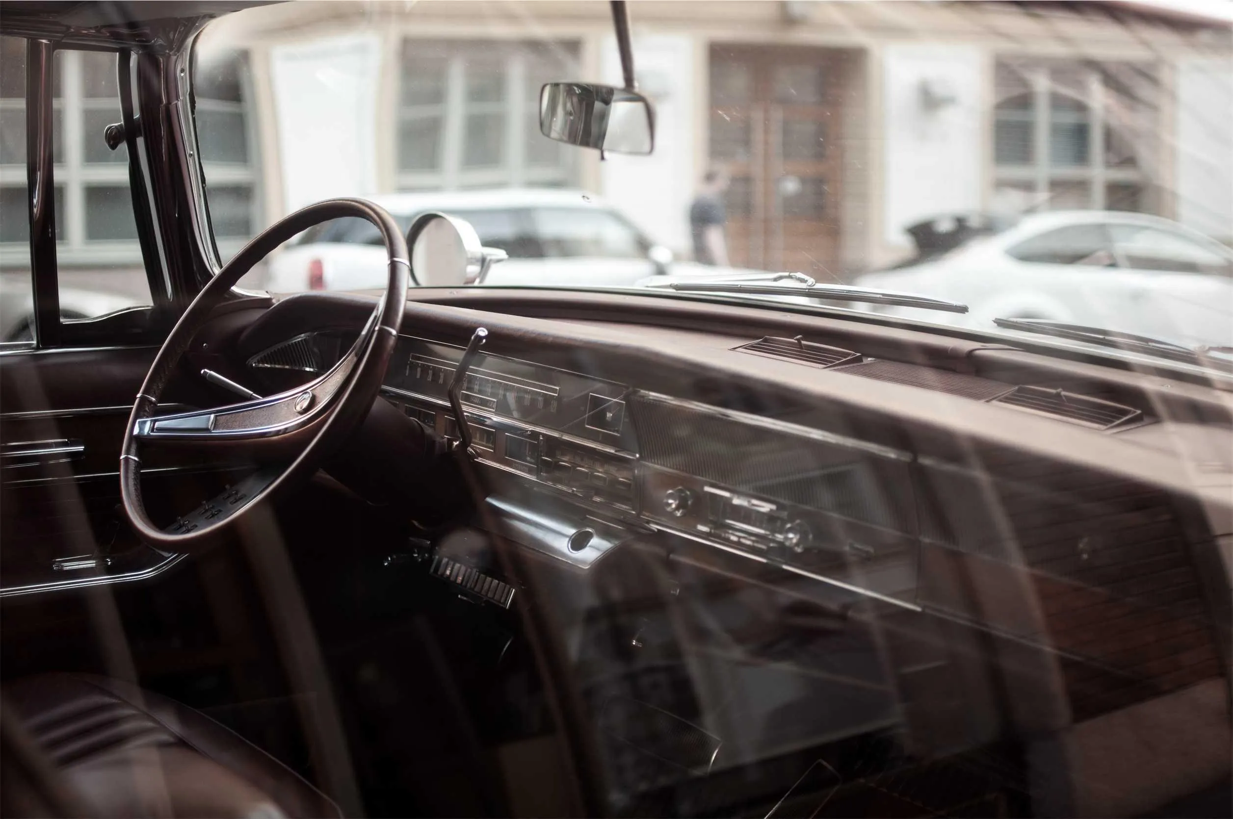 The worn interior of a classic car, light falling across the dashboard.